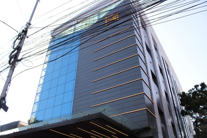 Angled view of the hotel building with blue glass and metal cladding