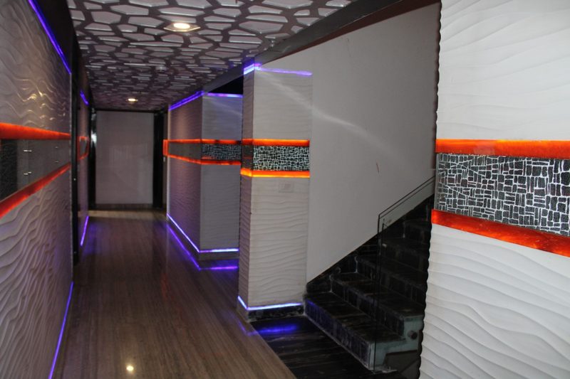 Corridor with a patterned ceiling and orange and purple accent lighting