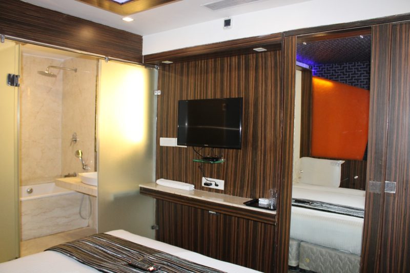 Bedroom with a wall-mounted TV and a glass-walled bathroom with bathtub