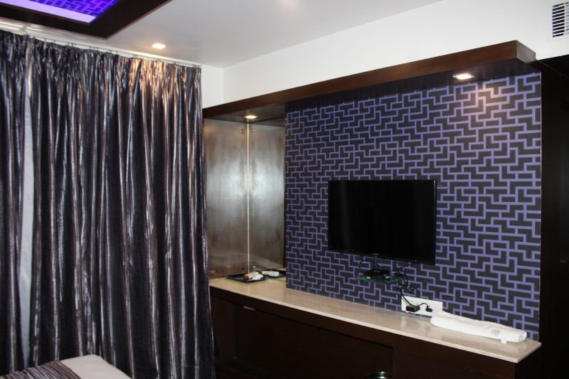 TV unit on a patterned purple wall beside grey curtains