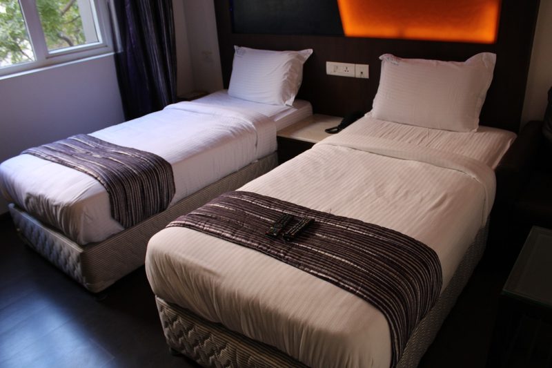 Twin beds with striped runners and a backlit headboard panel